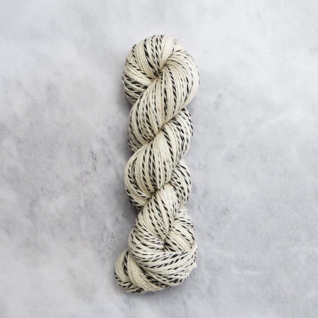 Pale yellow skein of yarn with black stripes.